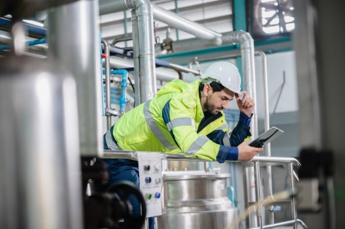 Portrait of handsome young male warehouse worker wearing safety vest jacket and hardhat